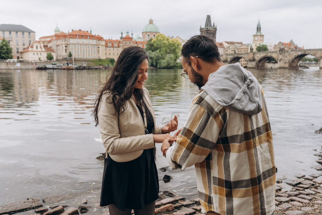 Couple during a surprise proposal with Charles Bridge in the background in Prague