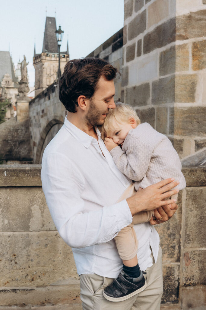 Don holding son during family photoshoot on Charles Bridge, Prague