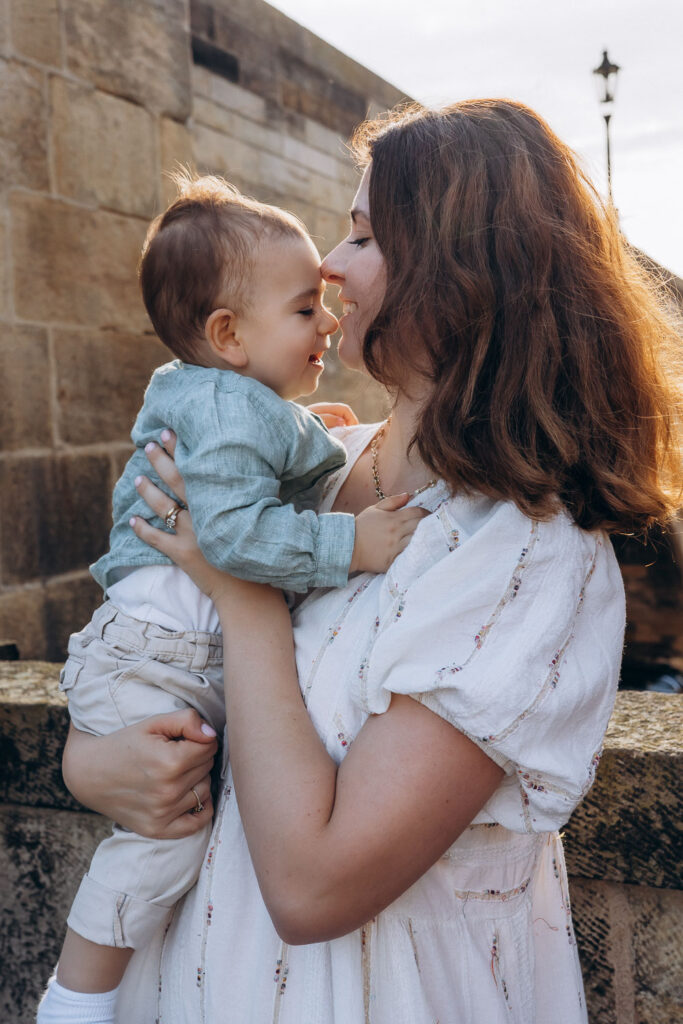 Mom holding son during family photoshoot on Charles Bridge, Prague