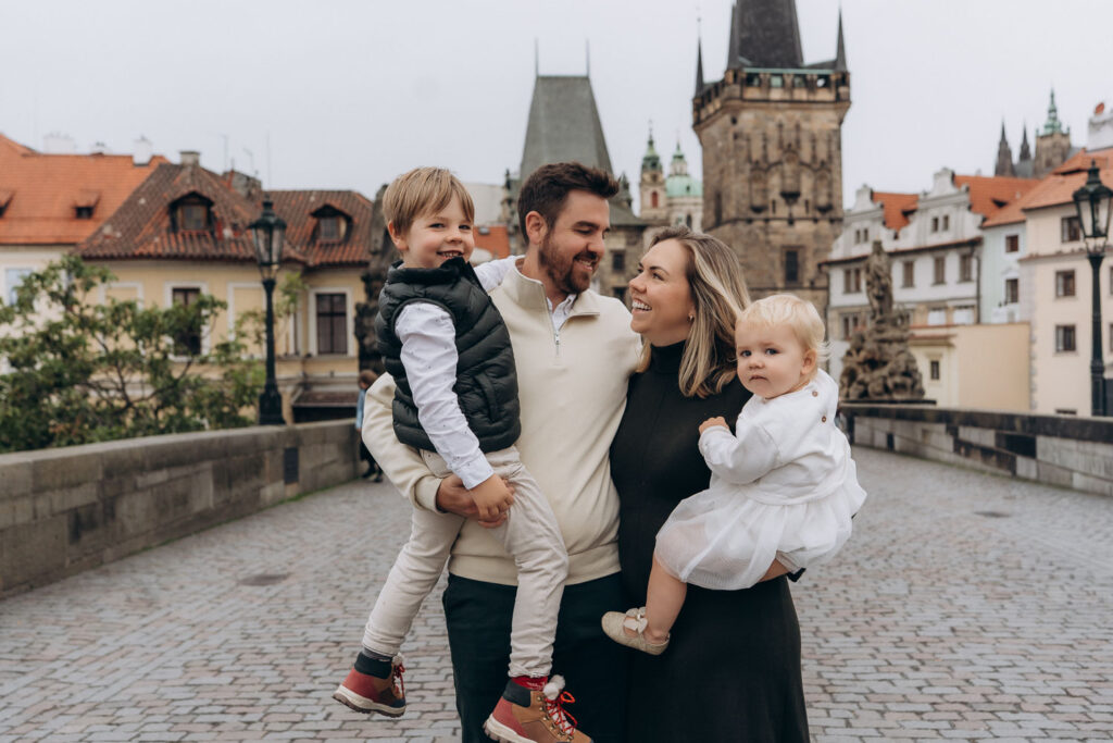 Parents with children capturing family moments on Charles Bridge, Prague