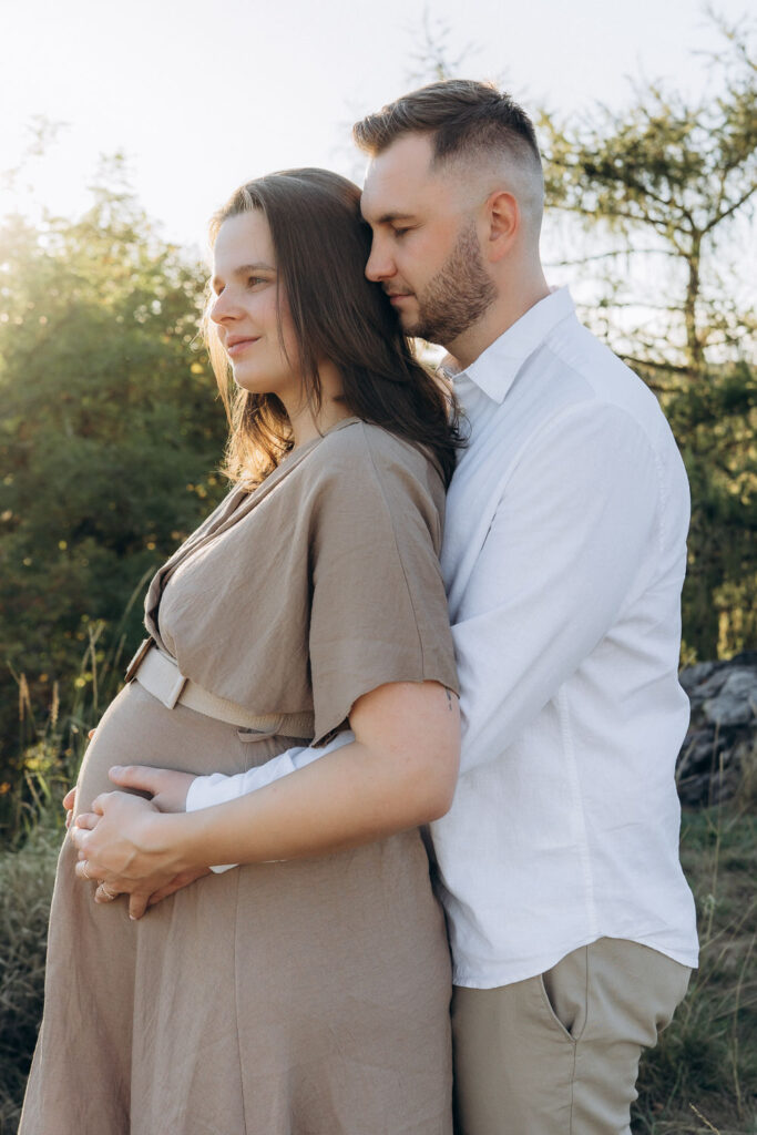 Expecting mother holding baby bump during summer photoshoot in Divoká Šárka, Prague