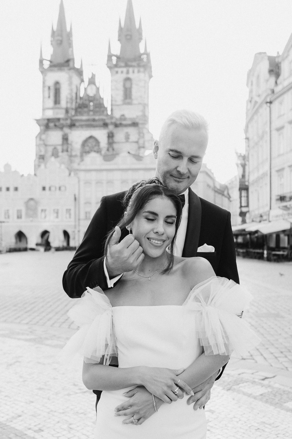 Bride and groom posing in front of Prague Old Town Square at sunrise