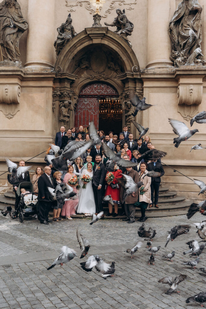 group of wedding guests captured after church ceremony in autumn light in Old Town Square